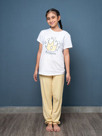 Girl wearing a white t-shirt with a 'Princess' design and yellow checkered pants against a blue wall.