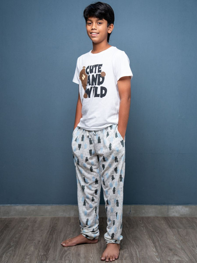 Child wearing a white t-shirt with text and patterned pants against a blue wall.
