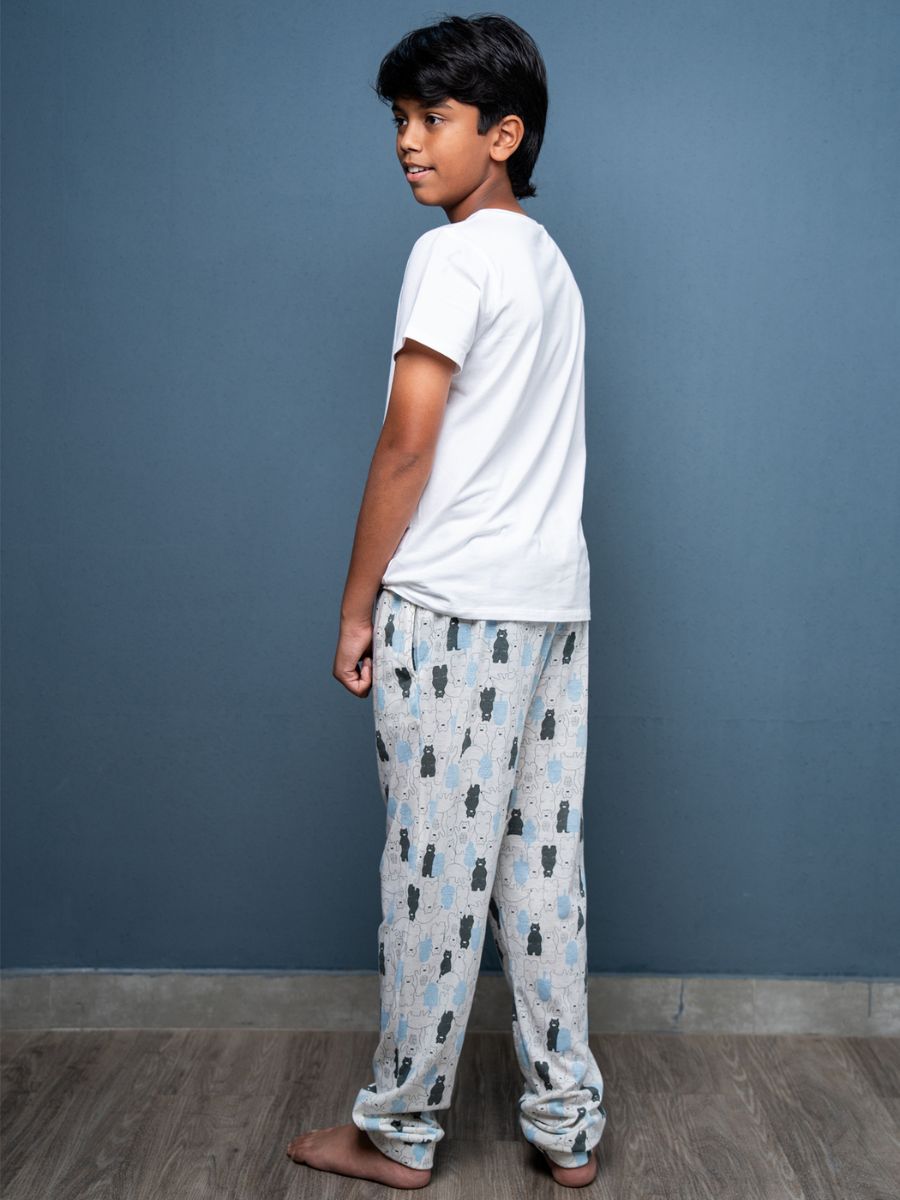 Child wearing a white t-shirt and patterned pajama pants against a blue wall.