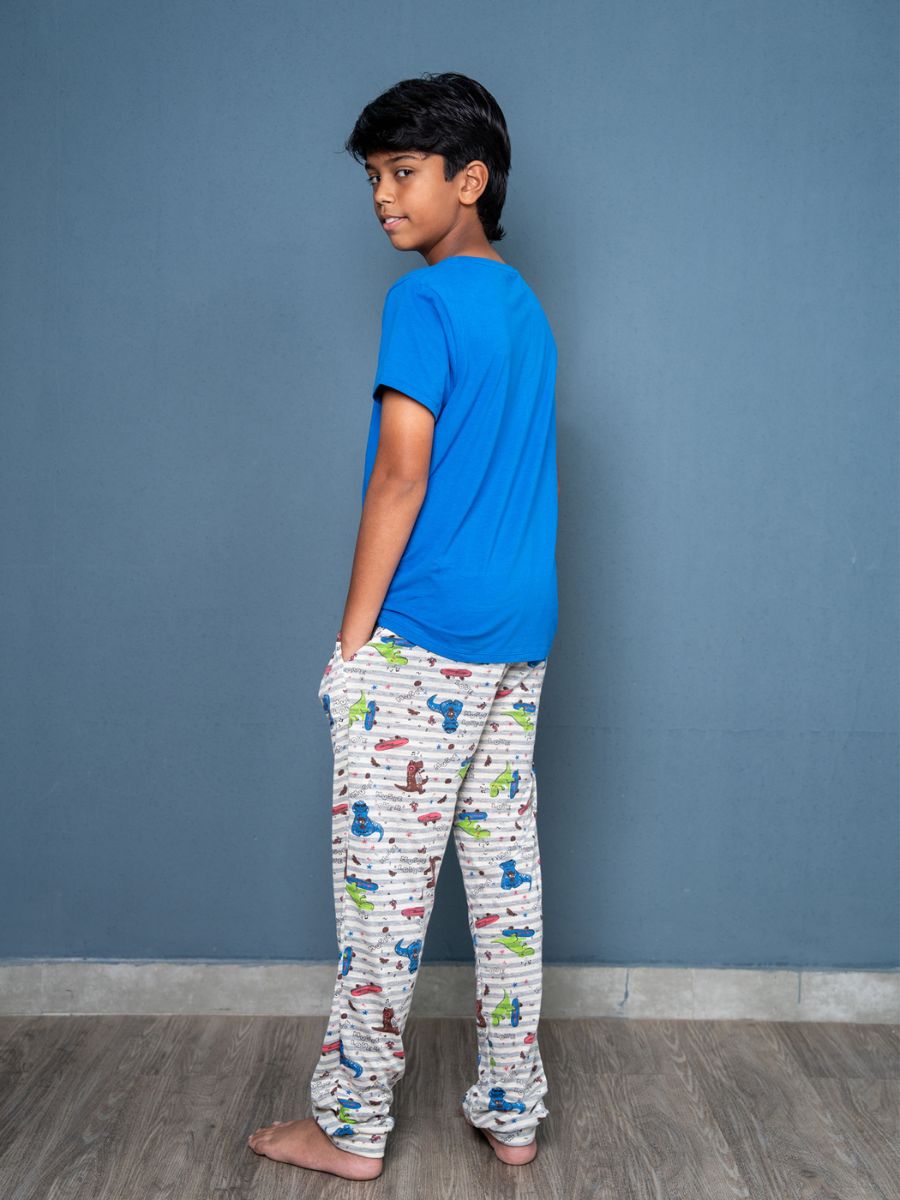 Child wearing a blue shirt and patterned pants against a blue wall.