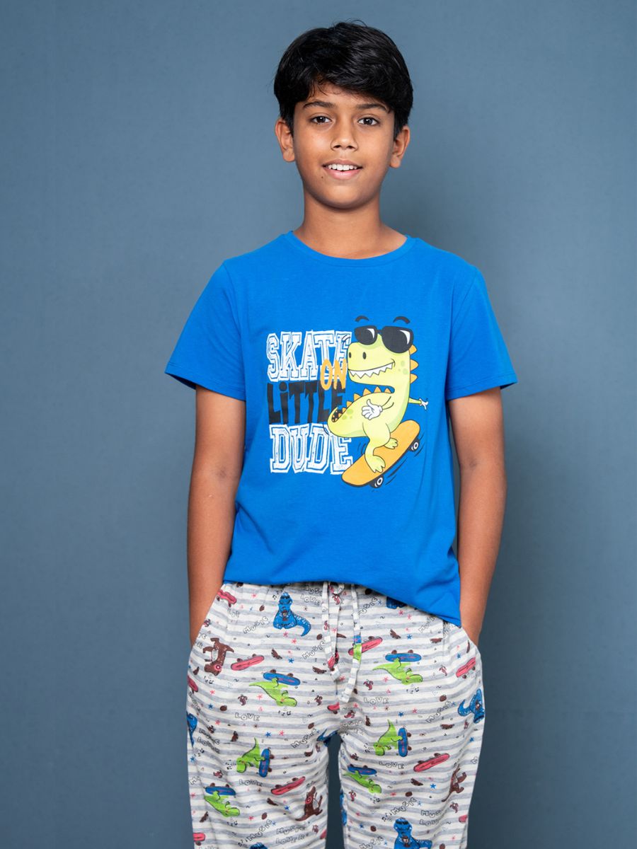 Child wearing a blue t-shirt with a graphic design and patterned pants on a gray background