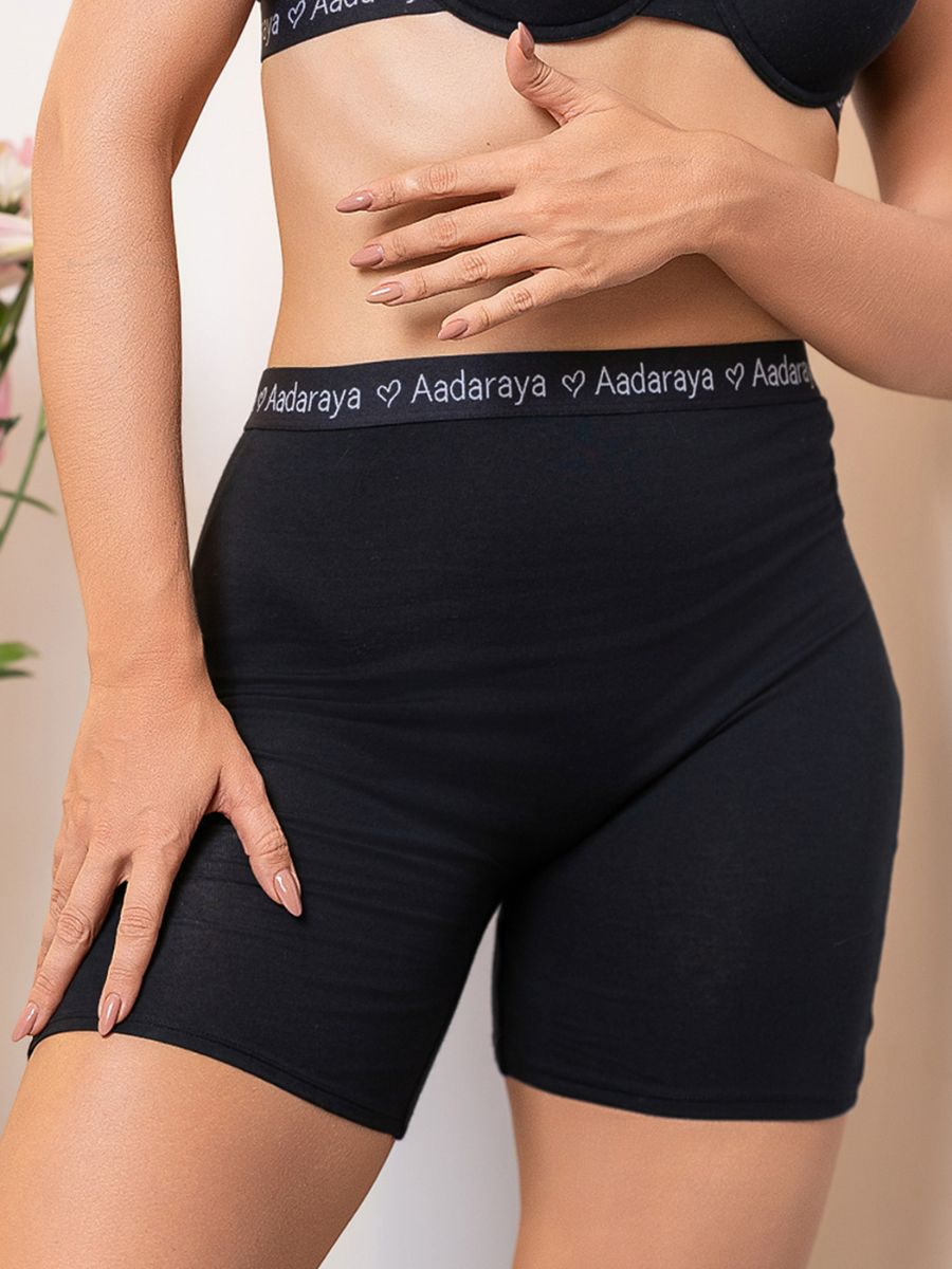 Person wearing black shorts with 'Aadaraya' waistband on a neutral background