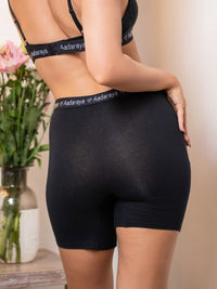 Person wearing black underwear with 'Aadaraya' branding, standing against a neutral background.