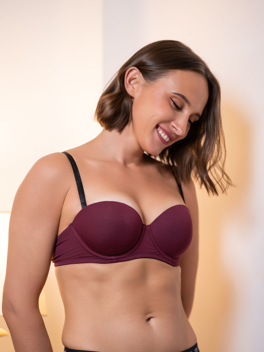 Woman wearing a maroon bra against a neutral background