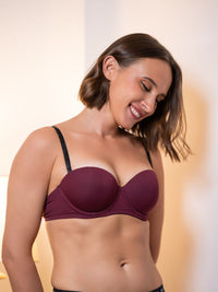 Woman wearing a maroon bra against a neutral background