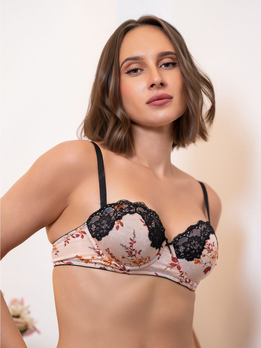 Woman wearing a floral bra with black lace details on a plain background