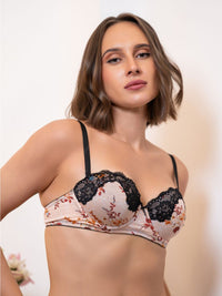 Woman wearing a floral bra with black lace details on a plain background