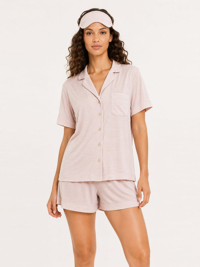 Woman wearing a pink pajama set with a matching visor on a white background