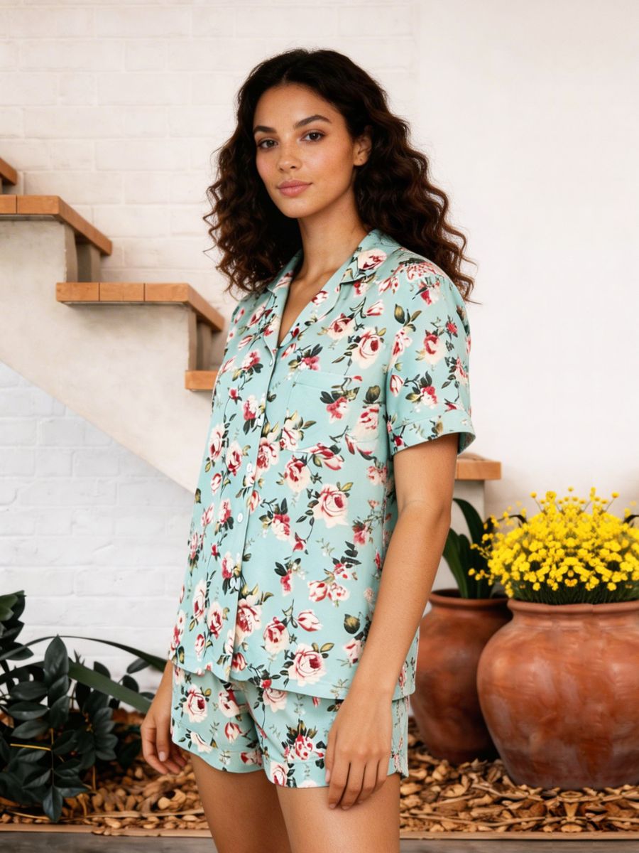 Woman wearing a floral pajama set standing in a home setting with plants.