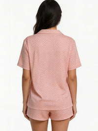 Woman wearing a pink polka dot pajama set on a white background