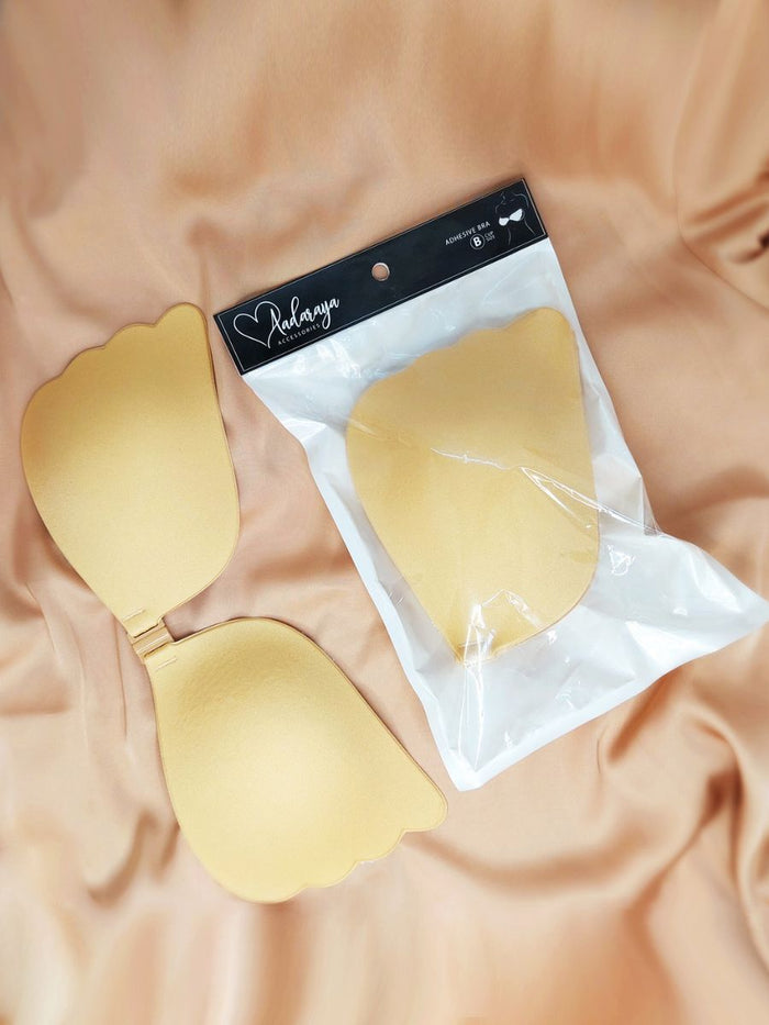 Gold adhesive bra pads on a beige fabric background