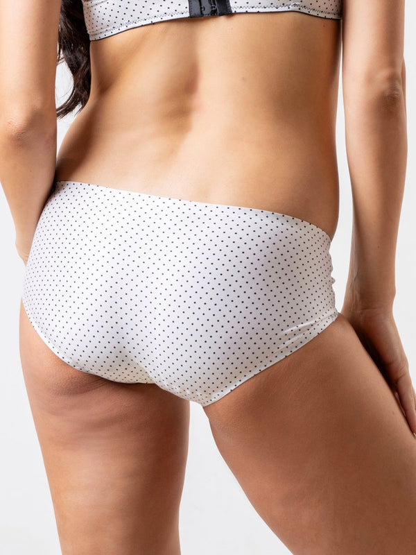 White polka dot bikini bottom worn by a person on a plain background