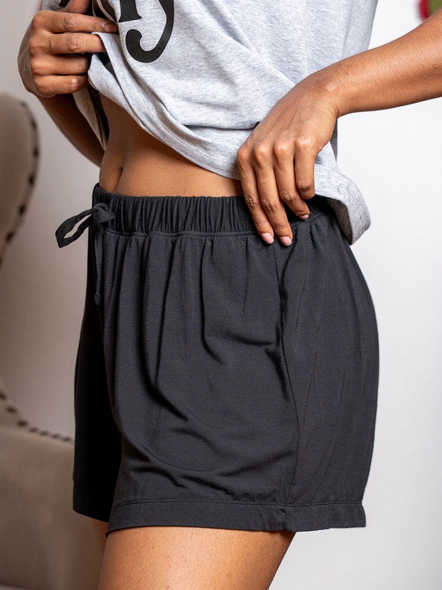 Person wearing black shorts with a plain background