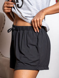 Person wearing black shorts with a plain background