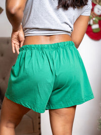 Person wearing green shorts and a gray top with a blurred background