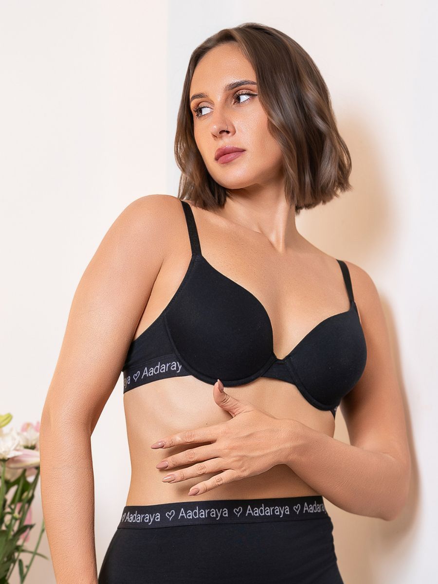 Woman wearing a black Aadaraya bra and panties set against a plain background