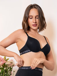 Woman wearing a black bra with 'Aadaraya' branding against a neutral background