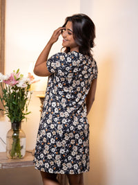 Woman wearing a floral dress in a softly lit room with flowers in the background