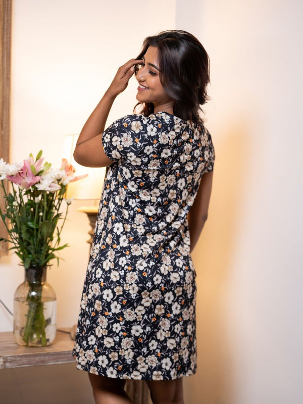 Woman wearing a floral dress in a softly lit room with flowers in the background
