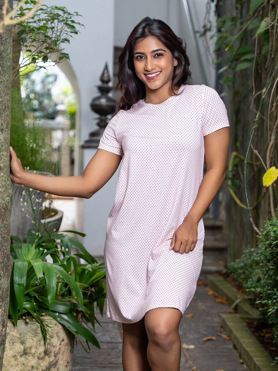 Woman in a light pink dress standing in a garden setting