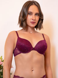 Woman wearing a purple lace bra against a plain background