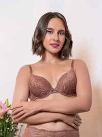 Woman wearing a brown lace bra and panties set against a plain background