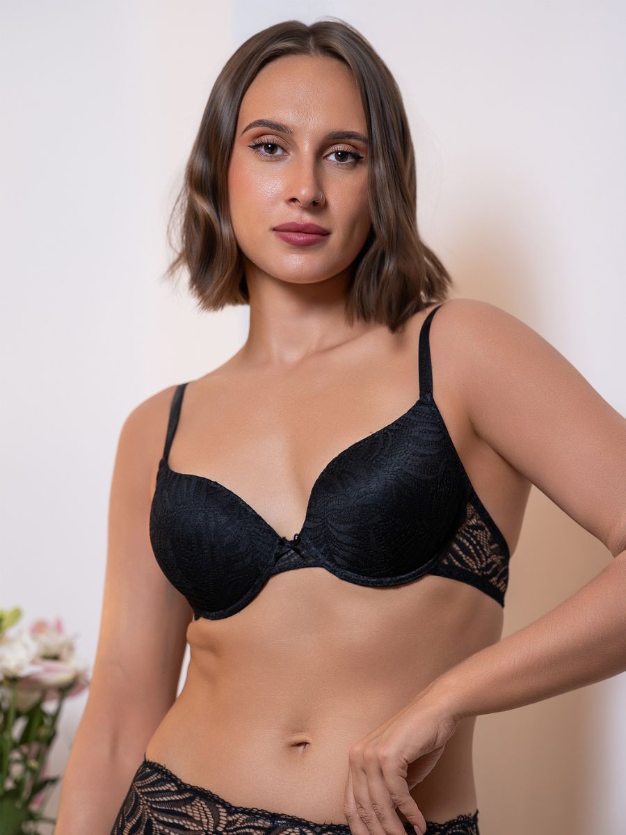 Woman wearing a black bra against a neutral background