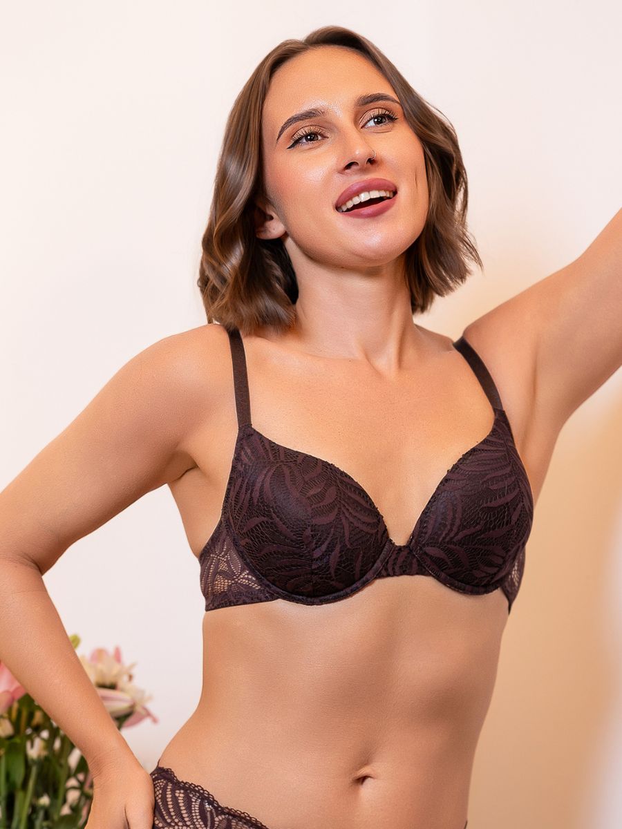Woman wearing a dark lace bra against a neutral background