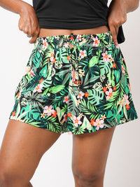 Tropical leaf patterned shorts worn by a person on a plain background
