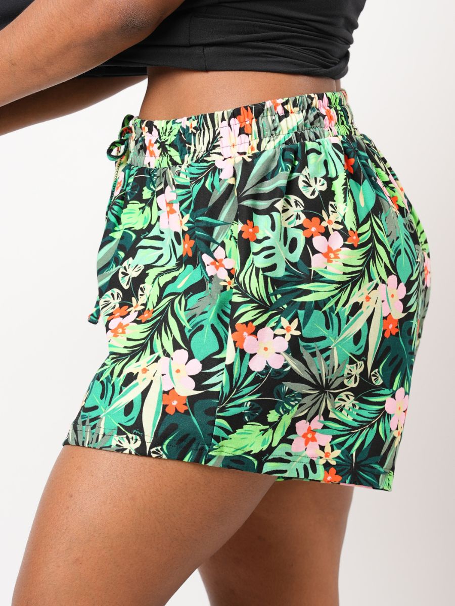 Tropical leaf patterned shorts worn by a person on a white background