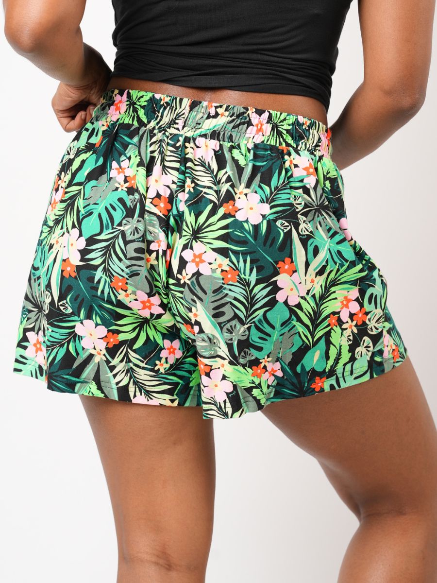 Person wearing a tropical leaf patterned skirt on a plain background