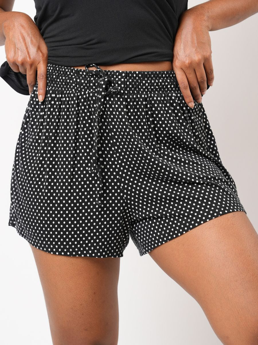 Person wearing black polka dot shorts on a plain background