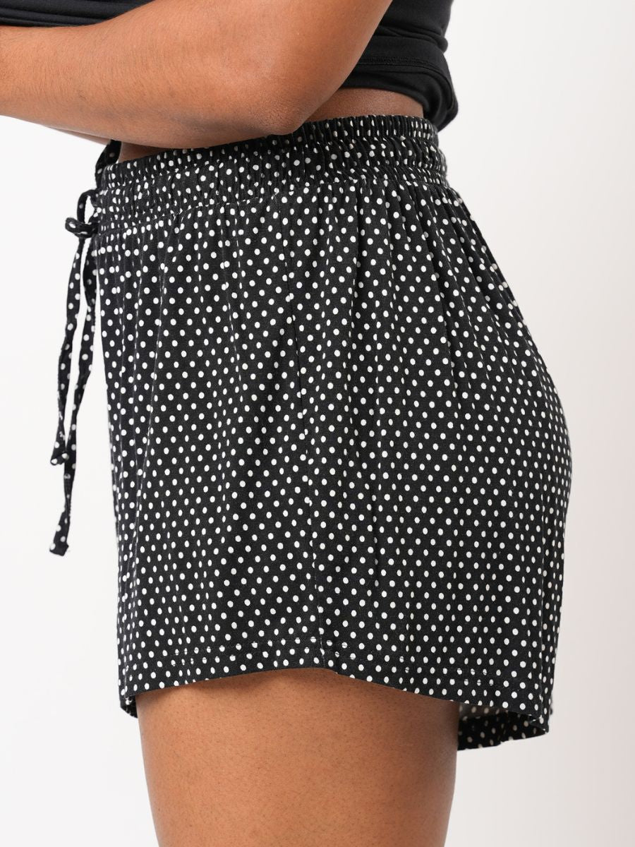 Black polka dot shorts with a tie waist on a white background