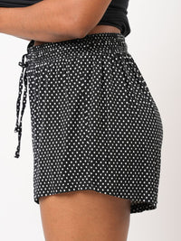 Black polka dot shorts with a tie waist on a white background