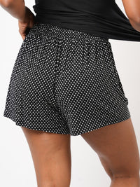 Black polka dot shorts worn by a person on a white background