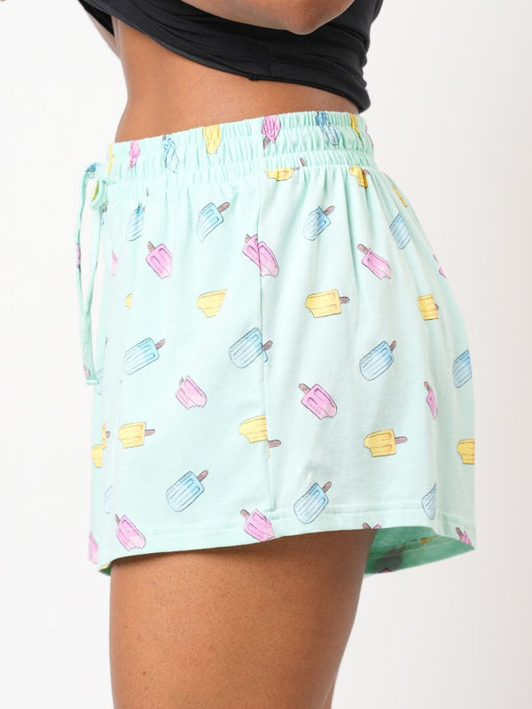 Light blue shorts with colorful popsicle pattern worn by a person on a white background