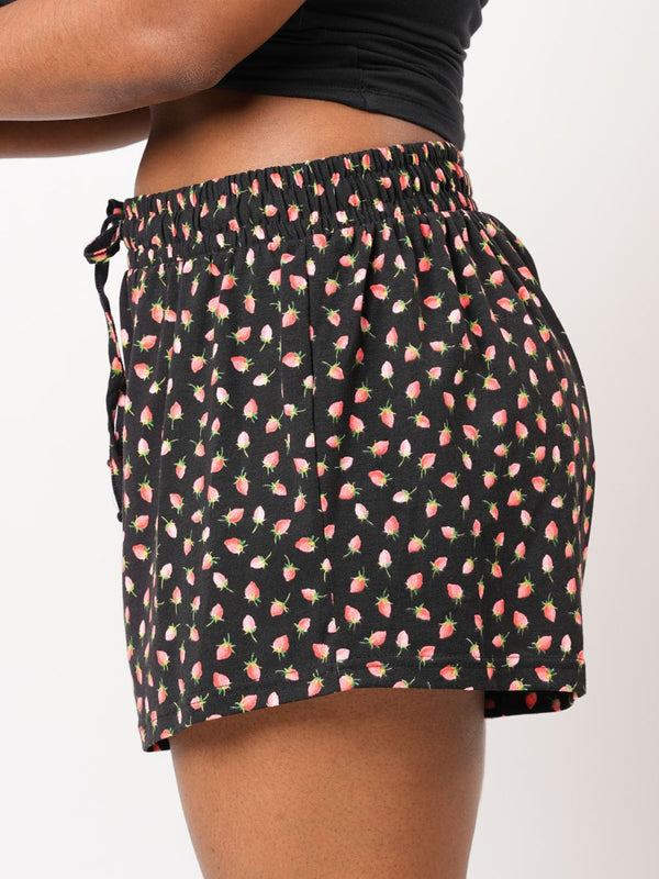 Black shorts with pink floral pattern worn by a person on a white background