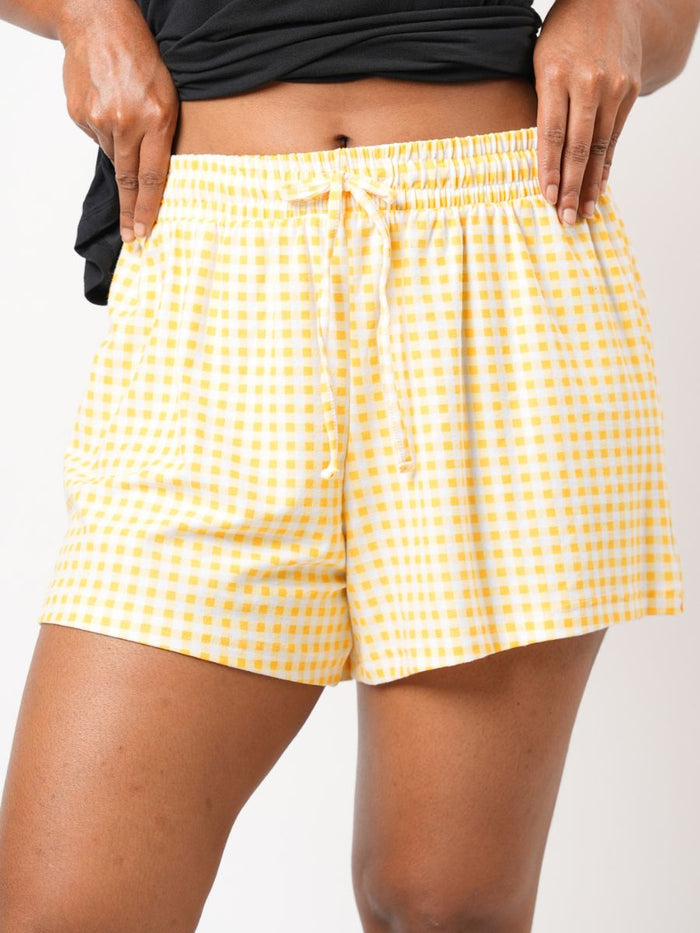 Yellow checkered shorts worn by a person on a white background