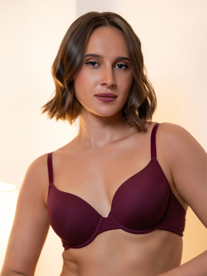 Woman wearing a burgundy bra against a neutral background
