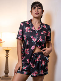Woman wearing a black floral pajama set in a softly lit room.