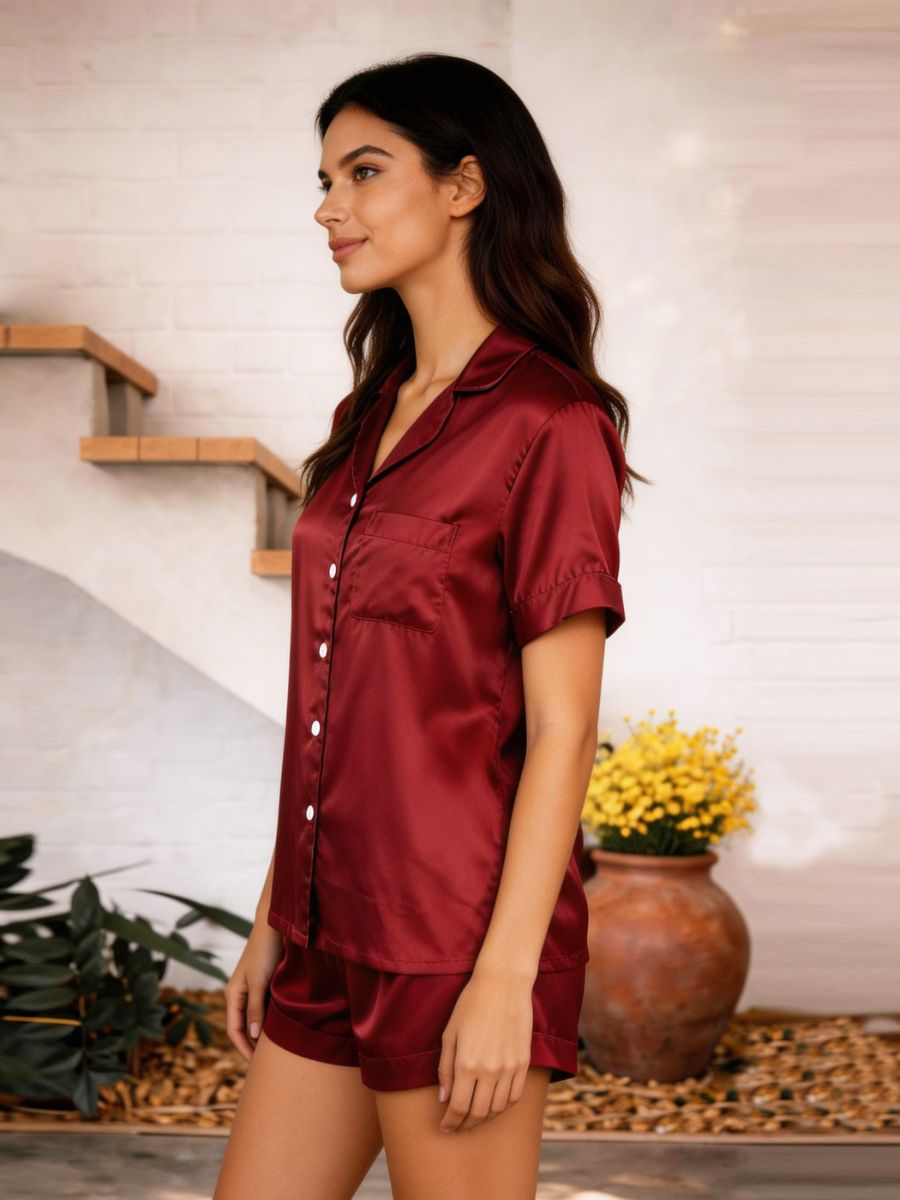 Woman wearing a burgundy satin pajama set standing in a home setting.