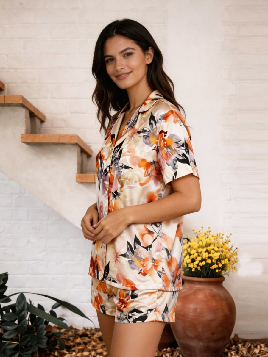 Woman wearing a floral pajama set standing in a home setting with plants and a vase.