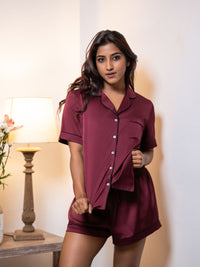 Woman wearing a burgundy pajama set in a cozy room.