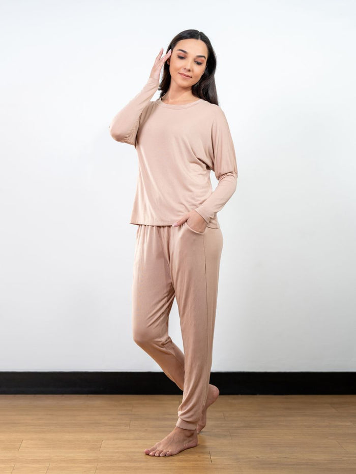 Woman wearing a beige pajama set against a white background