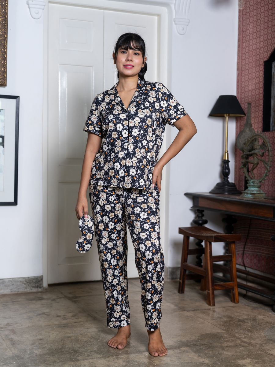 Woman wearing a floral pajama set in a room with a lamp and wooden furniture.