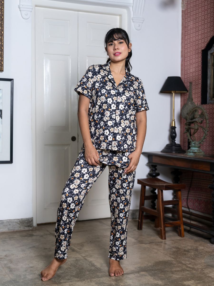 Woman wearing a floral pajama set in a room with a white door and wooden furniture.