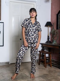 Woman wearing a floral pajama set in a room with a white door and wooden furniture.