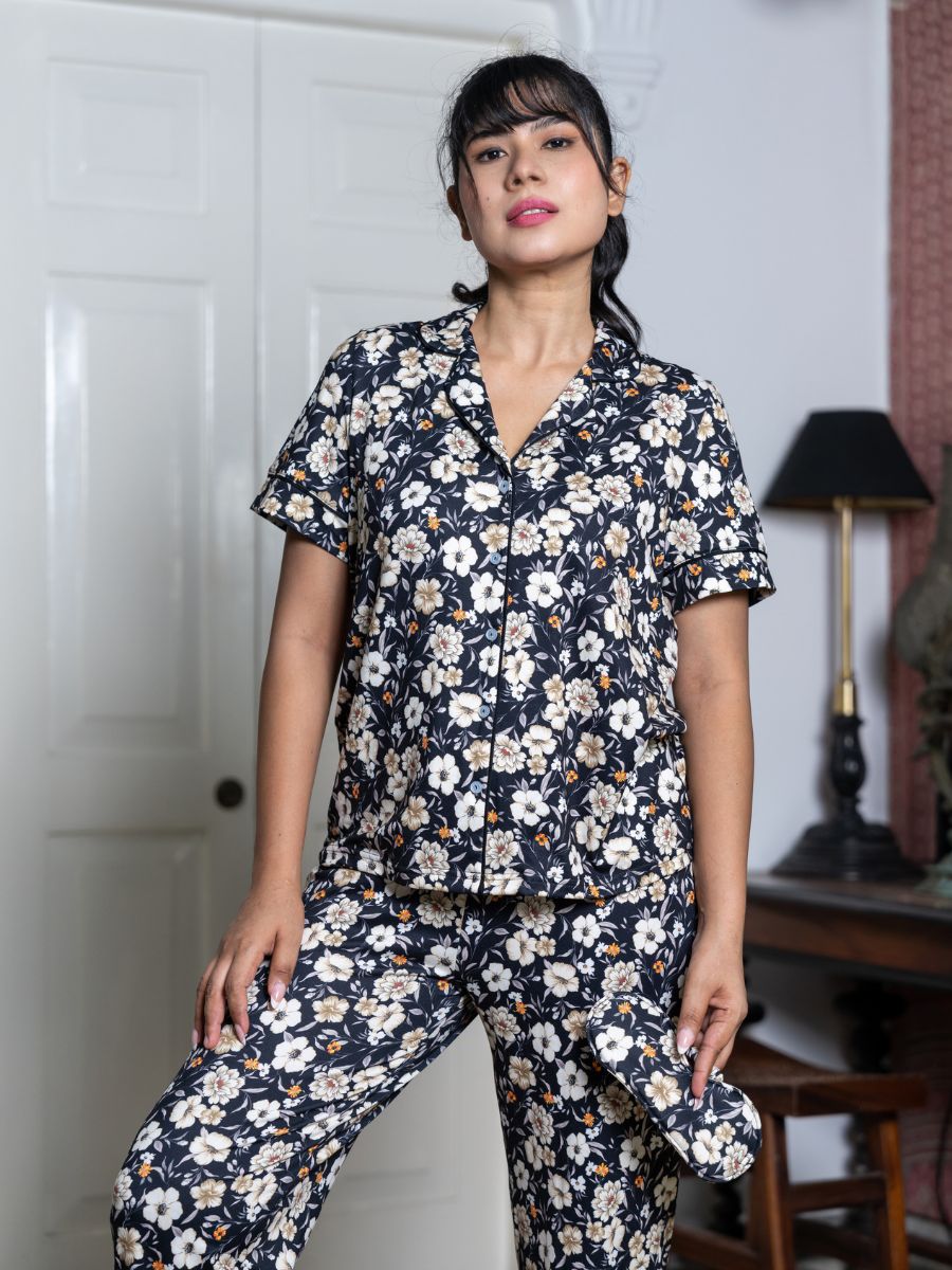 Woman wearing a floral pajama set in a room with a lamp and door.