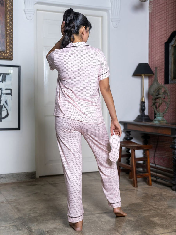 Woman in pink pajama set standing in a room with decor elements.