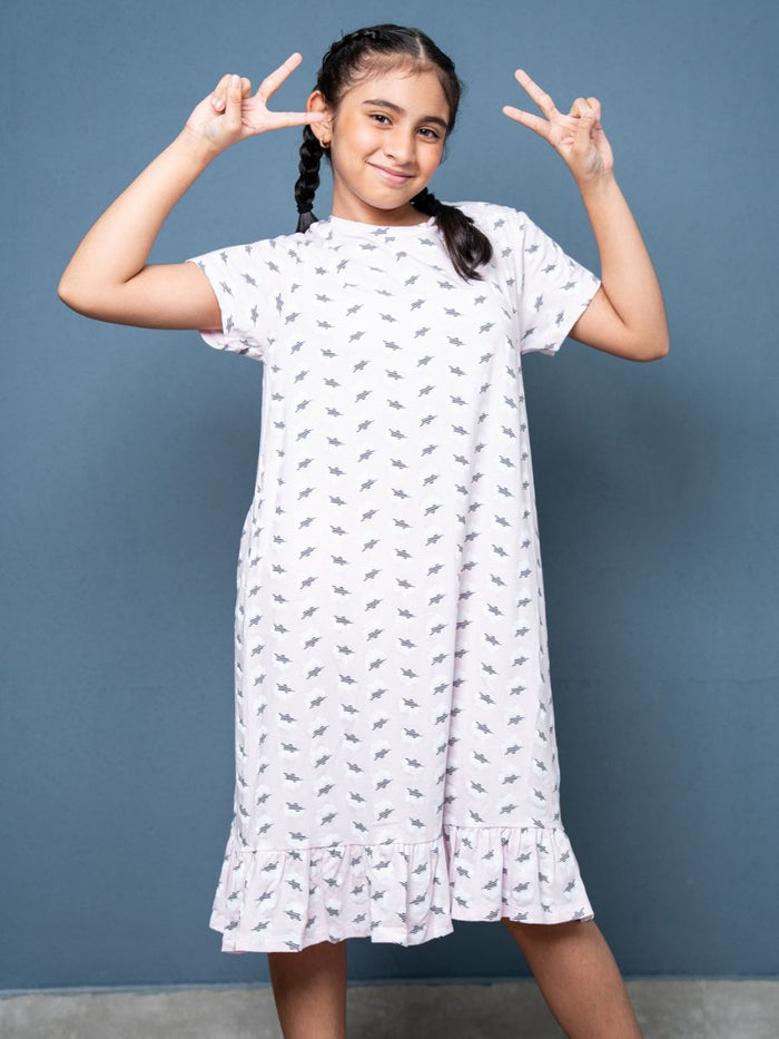 Young girl in a white dress with black patterns, making peace signs against a blue background
